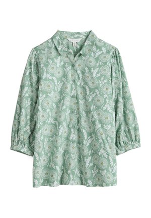 Groene blouse met lange mouwen met wit bloemenpatroon, knopen aan de voorkant, geplooide mouwen en een afgeronde kraag.