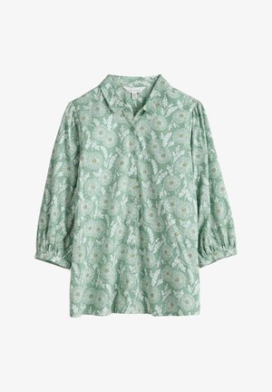 Groene blouse met lange mouwen met wit bloemenpatroon, knopen aan de voorkant, geplooide mouwen en een afgeronde kraag.