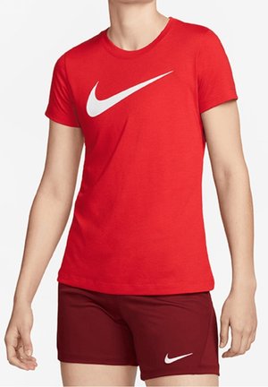 Person iført en rød Nike t-shirt med hvid swoosh-logo og matchende mørkerøde Nike shorts med hvidt swoosh-logo.