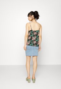 Top sem mangas preto com padrão floral e alças ajustáveis, combinado com uma saia de jeans azul-claro com bolsos traseiros e uma bainha reta.