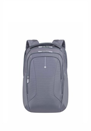 Sac à dos gris avec plusieurs compartiments zippés, bretelles rembourrées et un petit logo circulaire centré sur le panneau avant.