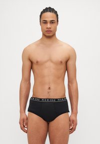 Schwarze Boxer mit elastischem Bund, der die weiße "PIER ONE"-Markierung trägt, schmal geschnitten, mit glatter Textur und ohne zusätzliche Muster oder Akzente.
