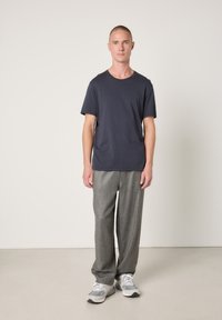 Navy cotton crew neck t-shirt, gray textured wide-leg trousers, and gray and white sneakers. Simple, relaxed design with minimal accents.