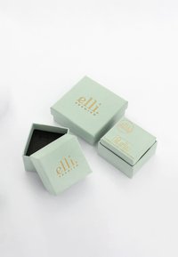 Scatole regalo verde menta con scritte dorate; una si apre rivelando un interno nero. Logo "elli" in evidenza sul coperchio di ogni scatola.