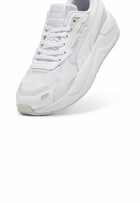 Bijela atletska tenisica s mrežastim i sintetičkim gornjištem, teksturiranim detaljima, zatvaranjem na vezanje i mekanim potplatom. PUMA logo na jeziku.
