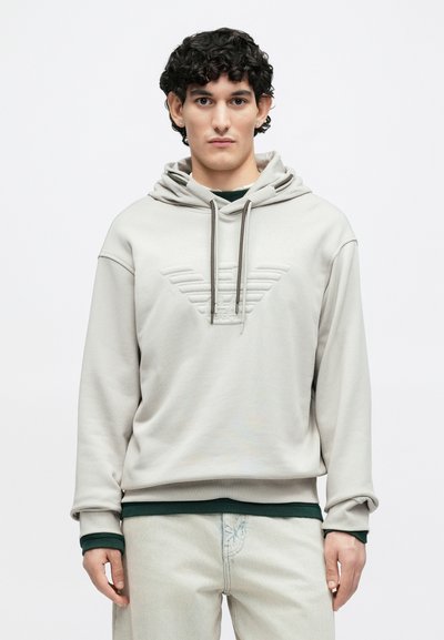 Ανοιχτό γκρι φούτερ με υφασμένο λογότυπο, ρυθμιζόμενα κορδόνια και στρώσεις πράσινου τελειώματος. Διαθέτει άνετη εφαρμογή και απαλό ύφασμα.