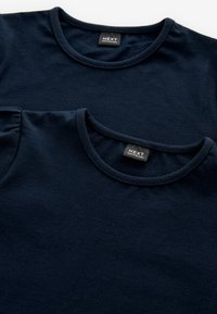 Marineblaue Baumwoll-T-Shirts mit runden Ausschnitten. Ein Shirt übereinander geschichtet, das eine ähnliche Stoffstruktur und Naht zeigt.