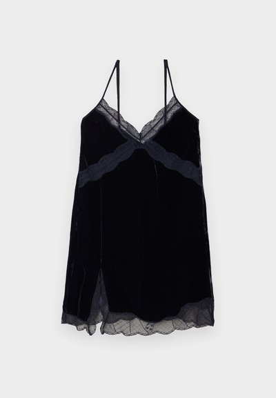 Čierna sametová cami s čipkovými detailmi. V-výstrih, nastaviteľné špagetové ramienka a mierne rozšírený strih s bočnými rozparkami.