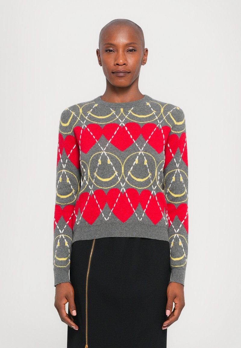Pulover gri cu modele geometrice roșii și galbene, având un guler rotund și mâneci lungi. Textură tricotată, design scurt.