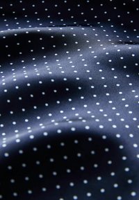 Tamsiai mėlynas audinys su lygiu tekstūra turi tolygiai išdėstytas baltas taškelis visame paviršiuje.