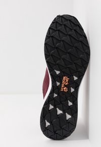 Black rugged shoe sole with triangular tread patterns and orange Jack Wolfskin logo, maroon upper partially visible against white background.