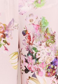 Bloemenbedrukte stof in zachtroze met verschillende bloemen en groen. Het ontwerp bevat levendige kleuren met een textuur en een gladde afwerking.