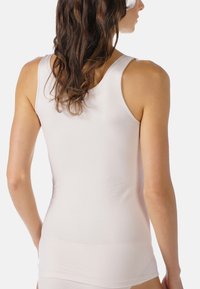Maglietta senza maniche bianca, aderente, con spalline larghe, realizzata in un materiale morbido. Mostrata di spalle, evidenziando una consistenza liscia e un design semplice.