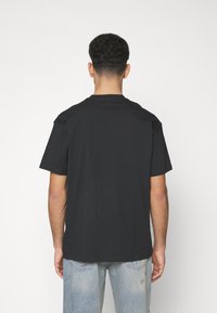 Black cotton t-shirt with a classic crew neck, short sleeves, and a relaxed fit, paired with light blue distressed denim jeans.