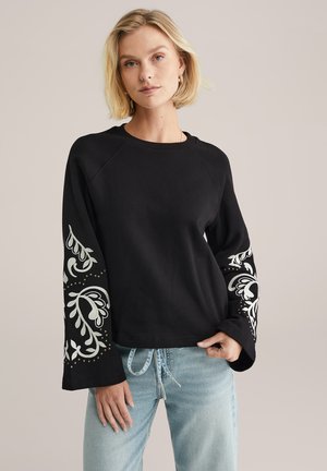 Zwarte sweatshirt met gestructureerde, uitlopende mouwen met lichtgrijze decoratieve accenten. Zacht, ontspannen model met een ronde halslijn.