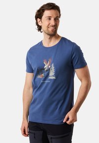 Blå bomulls t-shirt med rund hals och korta ärmar. Har en grafisk design av en örn mellan träd och en flod i dämpade färger.