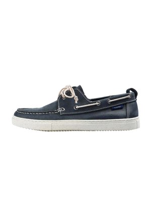 Zapato de barco de piel azul marino con suela de goma blanca, costuras en contraste y cordones beige. Presenta ojales de metal y una etiqueta con el logotipo.