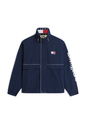 Veste bleu marine avec col montant, écusson Tommy Jeans sur la poitrine, nom de la marque imprimé sur la manche droite, et fermeture éclair avec boutons-pression.