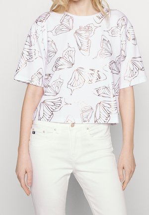 Valkoinen, lyhyt paita, jossa musta ja metallinhohtoinen ruusukullanvärinen perhonen, lyhyet hihat ja pyöreä kaula-aukko. Yhdistetty valkoisten farkkujen kanssa.