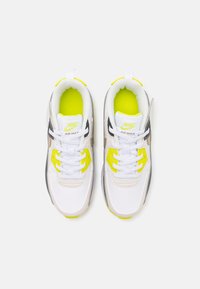 Nike Air Max teniske z belo in črno zgornjim delom ter neon rumenimi detajli, mrežasto teksturo, okroglimi vezalkami in oblazinjenim podplatom.