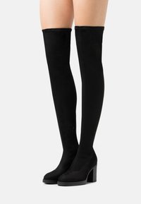 Bottes noires cuissardes en doux daim, dotées d'un talon épais et d'une fermeture éclair latérale pour un enfilage facile. Texture lisse et design élégant.