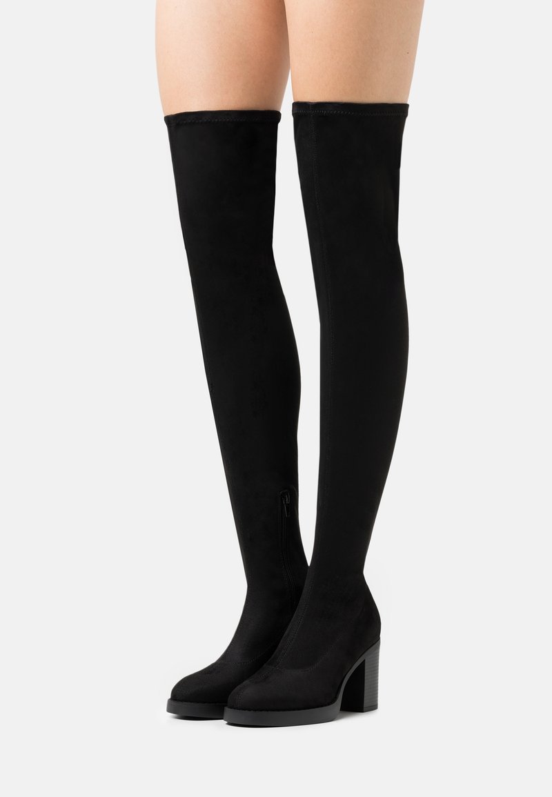 Bottes noires cuissardes en doux daim, dotées d'un talon épais et d'une fermeture éclair latérale pour un enfilage facile. Texture lisse et design élégant.