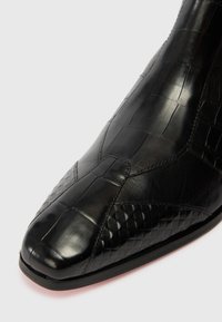 Čierne kožené dámske čižmy so štvorcovou špičkou a prešívaným, textúrovaným patchwork dizajnom na vrchu a po stranách.