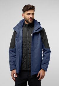 Veste multifonctionnelle bleue avec une couche intérieure isolée noire, dot ée d'une capuche, de poches zippées et de panneaux de couleur contrastante.