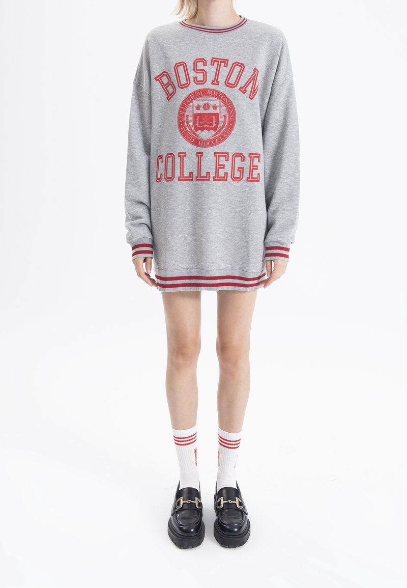 Šedá mikina s červeným nápisem "BOSTON COLLEGE" a emblémem. Má pruhované manžety a lem. Nosená s bílými ponožkami a černými platformovými botami.