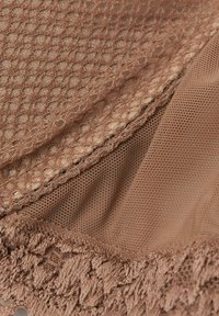 Textil marrón con un patrón texturizado que incluye una sección de malla y un borde suave con bucles. Los materiales incluyen telas de malla tejida y aireada.