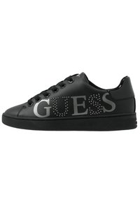 Zwarte synthetische sneakers met een rubberen zool, voorzien van een groot zilveren "GUESS" logo versierd met kleine studs aan de zijkant. Vetersluiting.