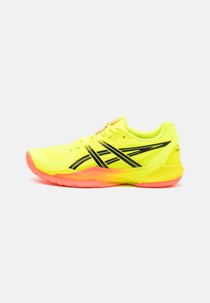 Knallig gelber Sportschuh mit schwarzen Streifen und korallenfarbener Sohle, seitlich auf weißem Hintergrund gezeigt.