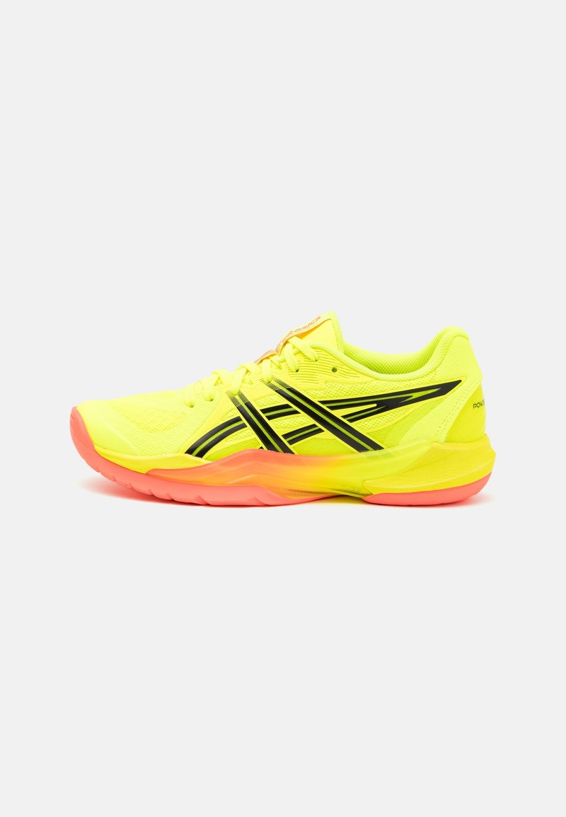 Chaussure de sport jaune vif avec des rayures noires et une semelle corail, vue de côté sur un fond blanc uni.