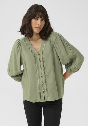 Groene, lichte blouse met een V-hals, pofmouwen en decoratieve kantafwerking aan de voorkant. Bevat knoopsluitingen en heeft een ontspannen pasvorm.