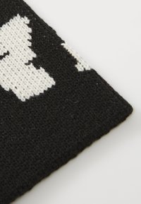 Vævet tekstil med sort og hvidt mønster; præget af en tekstureret overflade og kontrastfarver, der skaber et markant design.