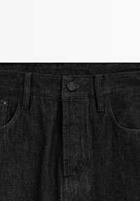 Sorte cowboybukser i denim med knaplukning, syningsdetaljer og to forlommer. Materialet har en struktureret, holdbar finish.