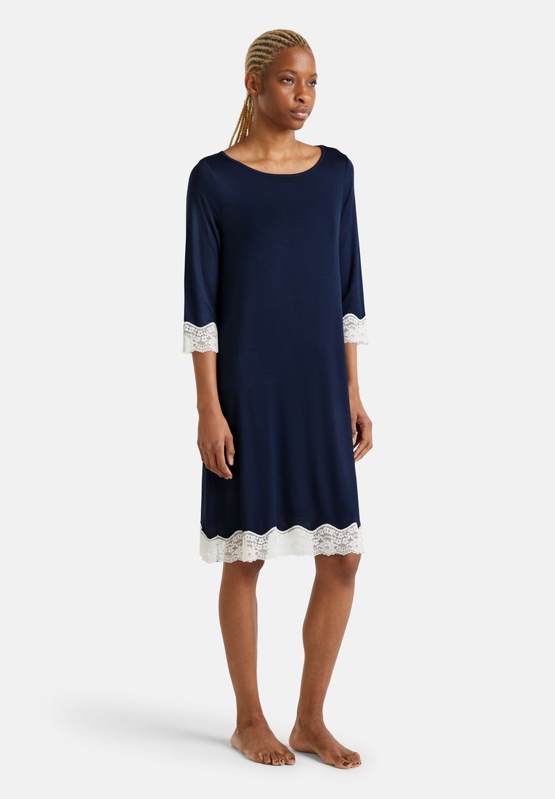 Abito blu navy con maniche 3/4, caratterizzato da dettagli in pizzo bianco all'orlo e ai polsini. Realizzato in tessuto morbido, design leggermente svasato.