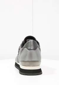 Sportssko med en grå metallisk finish, som har en smidig design, texturerat tyg, svart gummisula och en subtil reflekterande detalj på hälen.