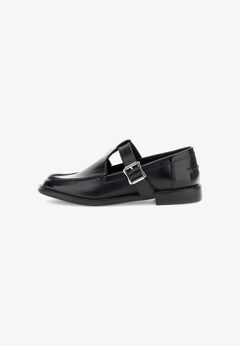Zapato de cuero negro con punta redondeada, detalle troquelado y correa ajustable con una hebilla de plata. Acabado suave con un tacón bajo.