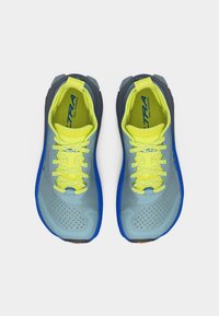 Ζευγάρι παπουτσιών για τρέξιμο σε μονοπάτια, μπλε και νέον κίτρινα, με κορδόνια και λογότυπο "Altra", φωτογραφημένα από ψηλά σε λευκό φόντο.