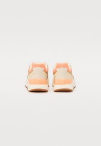 Sport shoes featuring a light beige mesh upper, orange accents, and textured rubber sole, with a padded collar and contrasting heel detail.