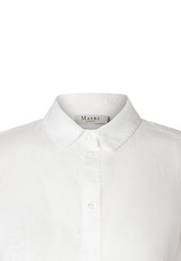 Camicia bianca con colletto classico, realizzata in tessuto leggero, con una sottile texture e tre bottoni frontali.