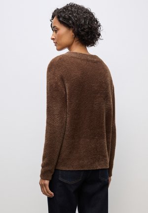 Brauner, flauschiger Strickpullover mit lässiger Passform. Hat einen runden Halsausschnitt und lange Ärmel, kombiniert mit dunklen Denim-Jeans.