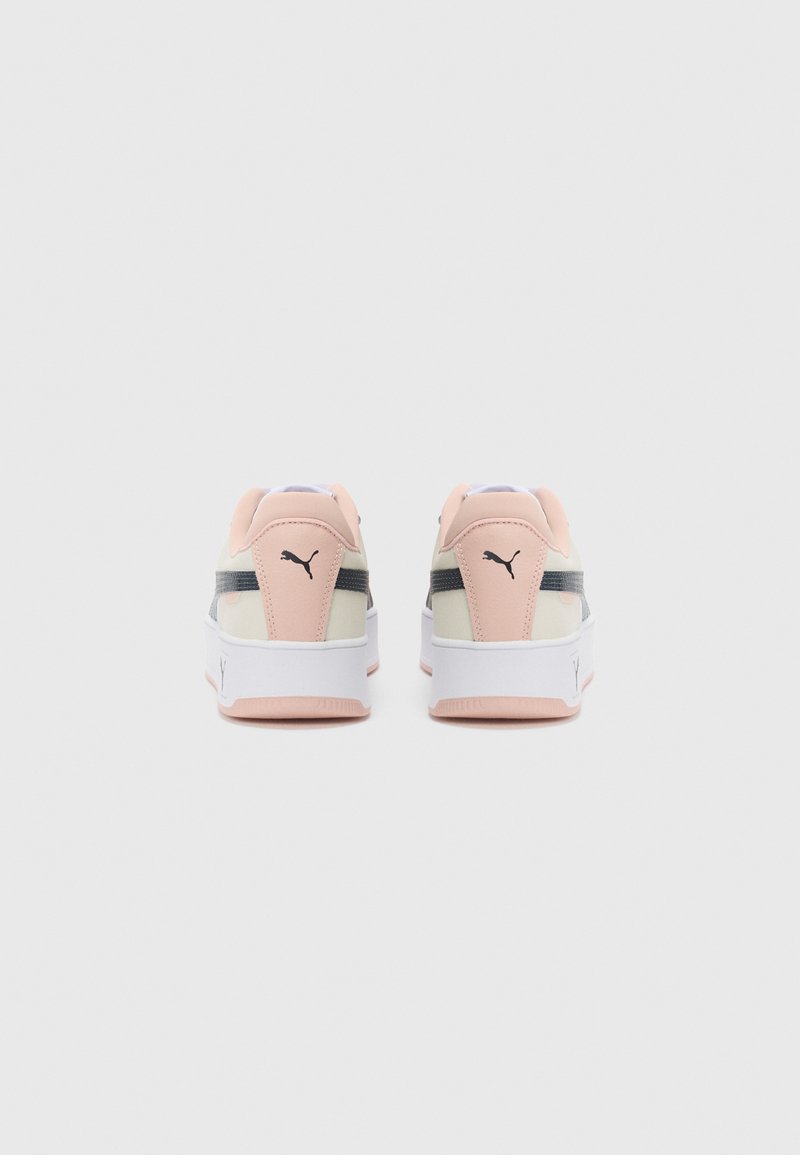 Un par de zapatillas Puma en beige y rosa vistas desde atrás, con el logo negro de Puma y una suela blanca gruesa, sobre un fondo blanco.
