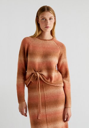 Pull en tricot avec un dégradé de léger orange à marron, dotée de manches longues et d'un détail de taille nouée. Texture douce, coupe décontractée.