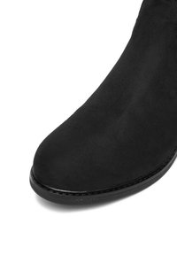 Czarne zamszowe buty z okrągłym noskiem i gładką czarną podeszwą, pokazane na białym tle.