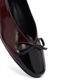 Bordeaux patenten leren flats met een ronde zwarte neus, voorzien van een klein zwart strikje aan de voorkant en een gladde binnenvoering.
