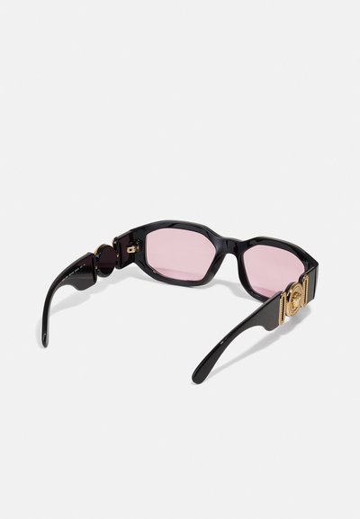 Sorte acetat solbriller med rosa linser, oktagonal form, gullakenter på stengene, og slanke svarte stenger med blank finish.