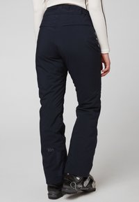 Marineblauwe skibroek met een gladde, waterafstotende afwerking, voorzien van een hoge taille en subtiele branding op het been. Gevoerde tailleband voor comfort.