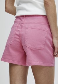 Pantalones cortos de algodón rosa con un ajuste relajado, que cuentan con dos bolsillos traseros y doble costura en los dobladillos para mayor durabilidad.